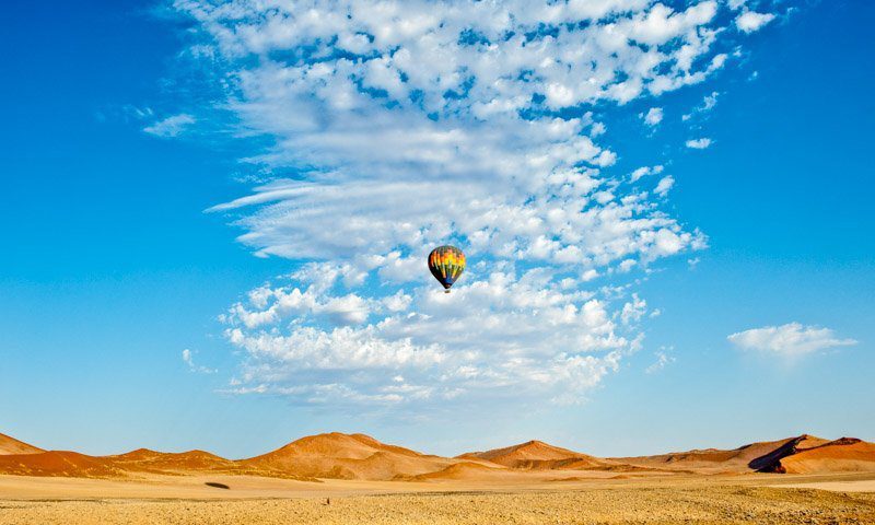 Hot air balloon drifting over Sossusvlei dunes in Namibia, captured by a travel photographer specializing in African landscapes